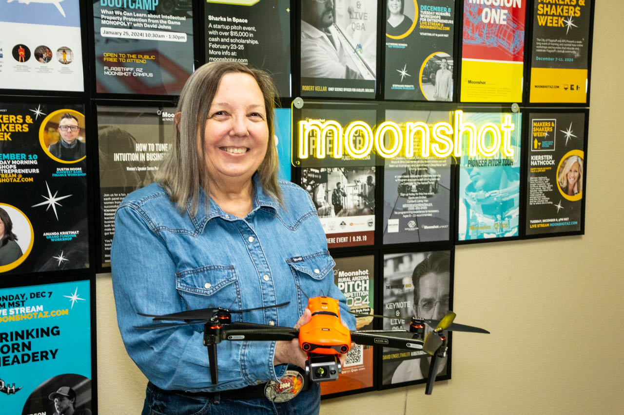 Ariel Strong of FireFlight stands in front of the moonshot sign, holding a drone.